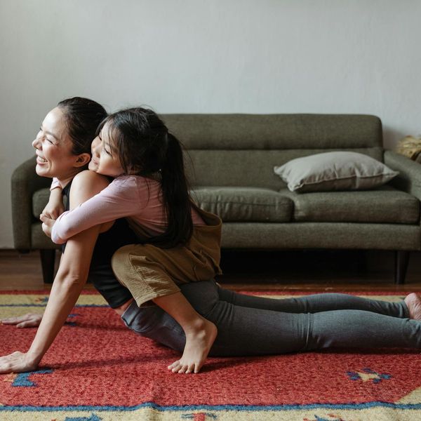 Smiling person stretching gently in a brightly lit room, conveying a sense of well-being.